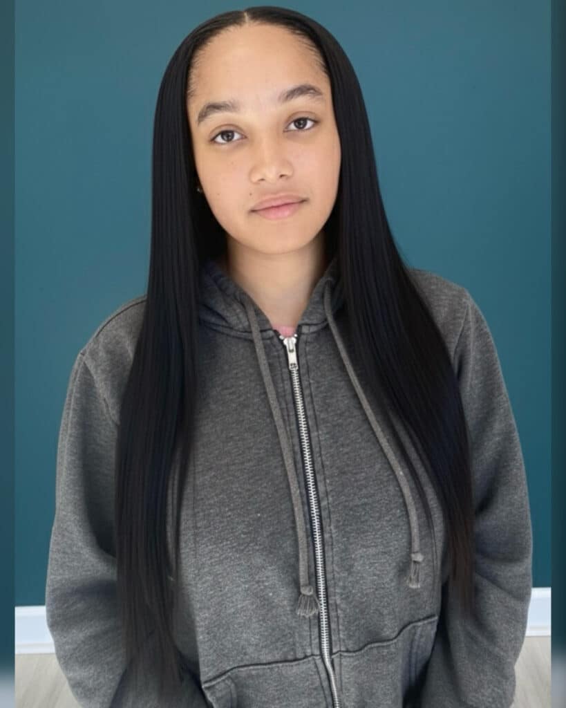 Woman with sleek, straight traditional sew-in wearing a gray hoodie