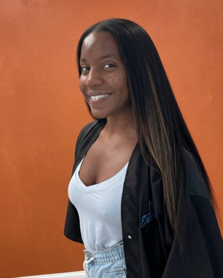 Woman with sleek, straight traditional sew in hairstyle smiling in profile