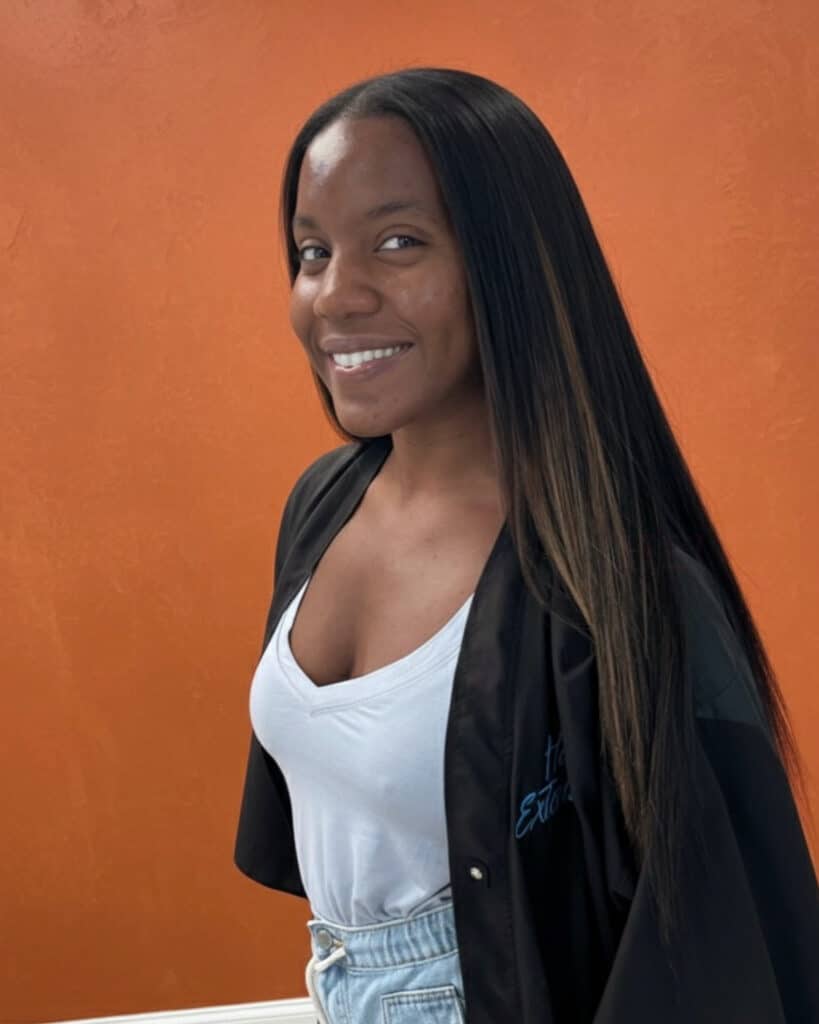 Woman with sleek, straight traditional sew in hairstyle smiling in profile